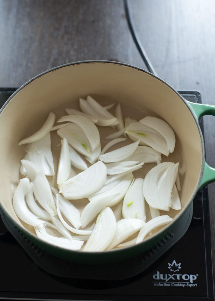 Sliced onions are placed in a braising pot.