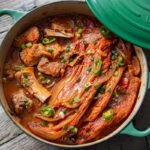 A pot of kimchi jjim is showing braised kimchi and pork ribs inside.