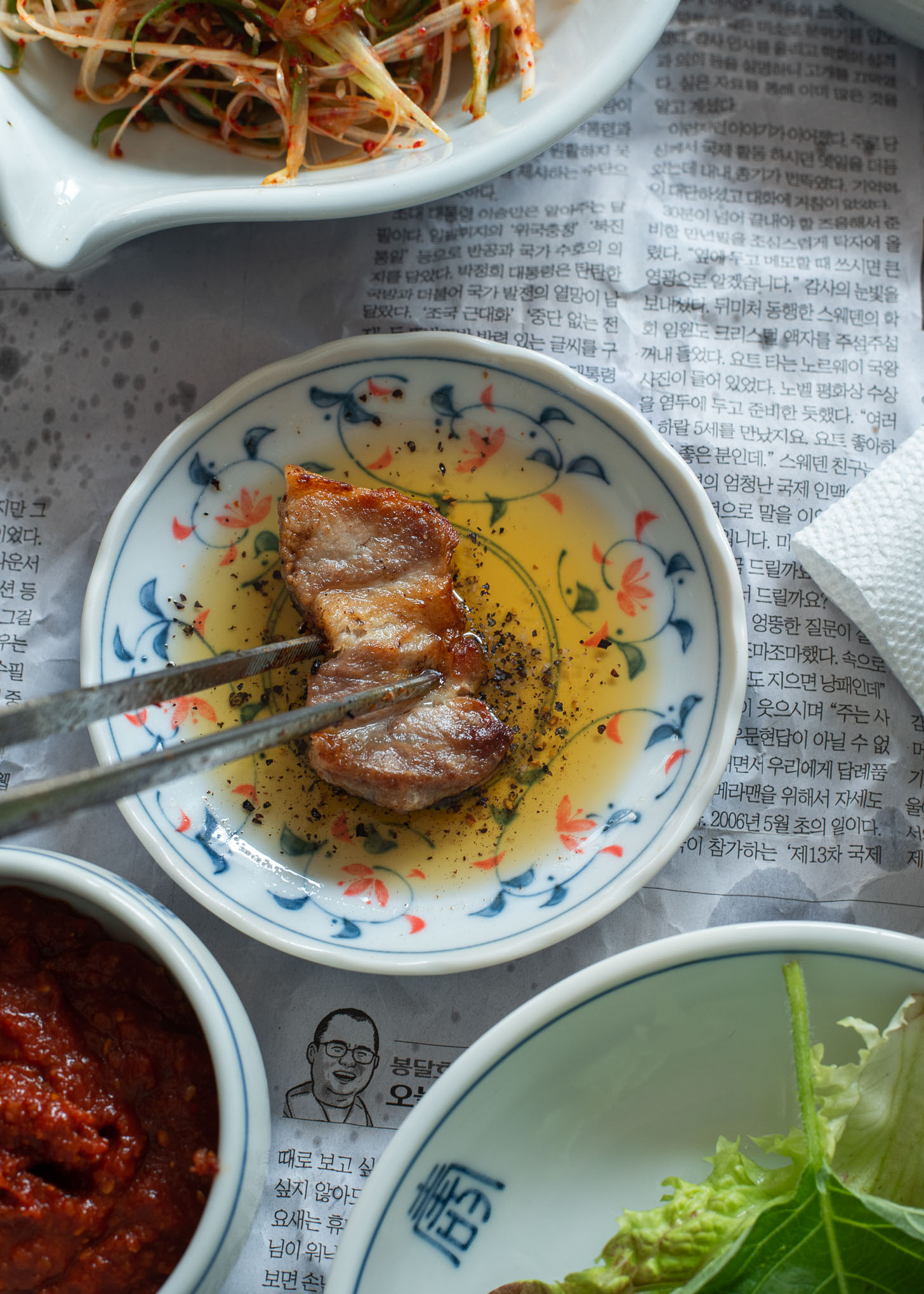 A piece of grilled samgyupsal dipping in sesame oil.