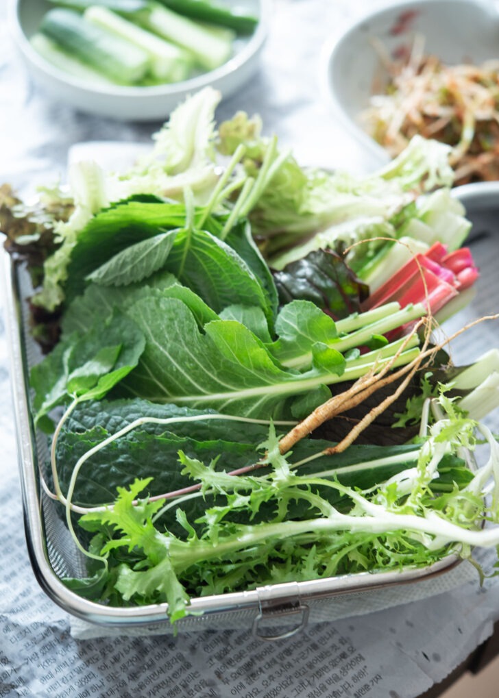 A variety of lettuce is collected in a basket for making samgyupsal BBQ.