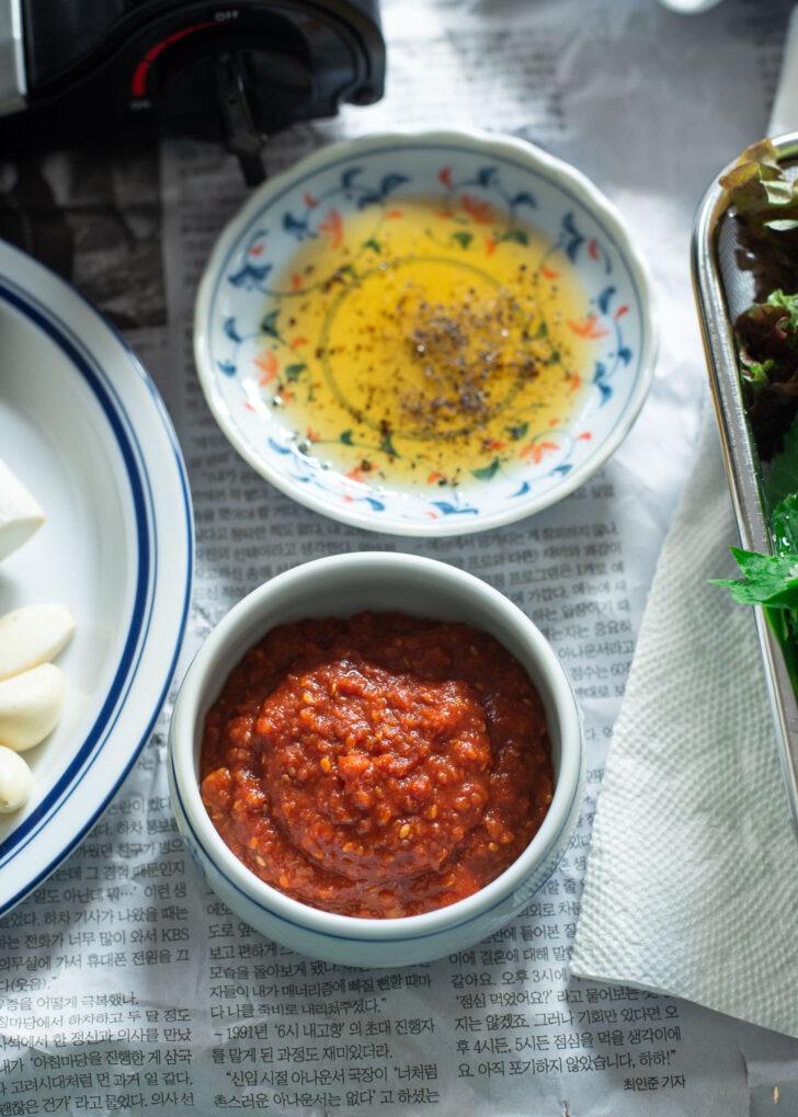 Ssamjang in a small bowl is next to sesame oil.