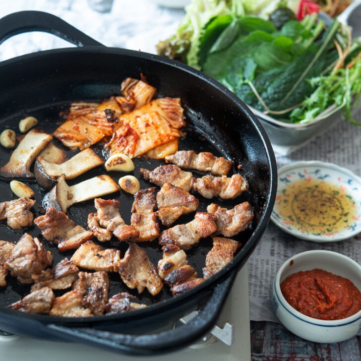 Korean BBQ table is filled with grilled samgyupsal and other side dishes.