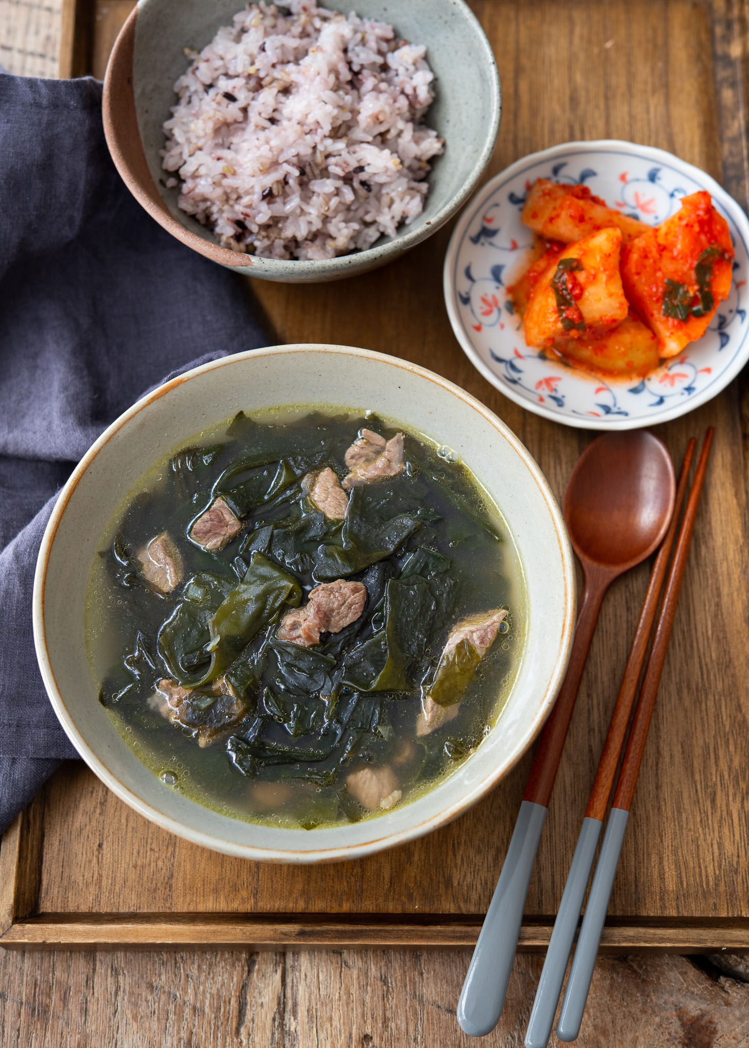 A bowl of seaweed soup served with rice and kimchi.
