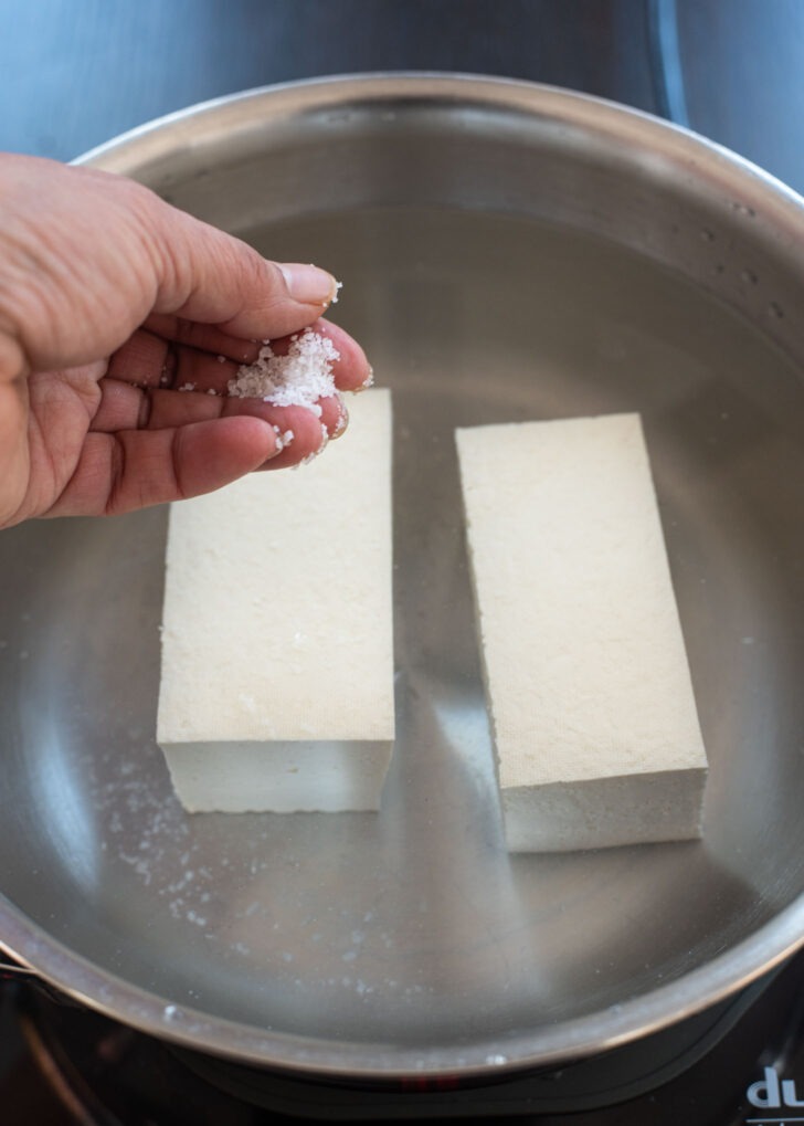 Tofu blocks are simmered in water with salt.