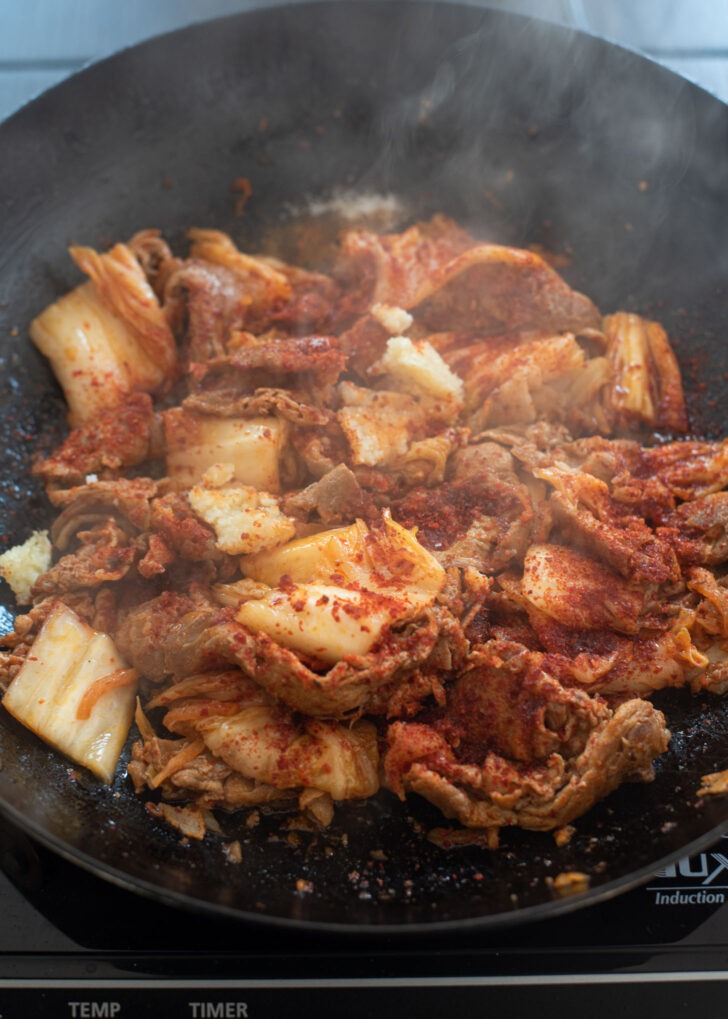 Pork and kimchi are stir-frying together until soft.