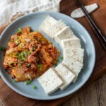 Korean tofu slices and stir fried kimchi are presented together on a plate.