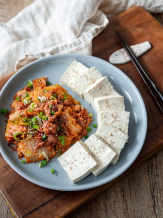 Korean tofu slices and stir fried kimchi are presented together on a plate.