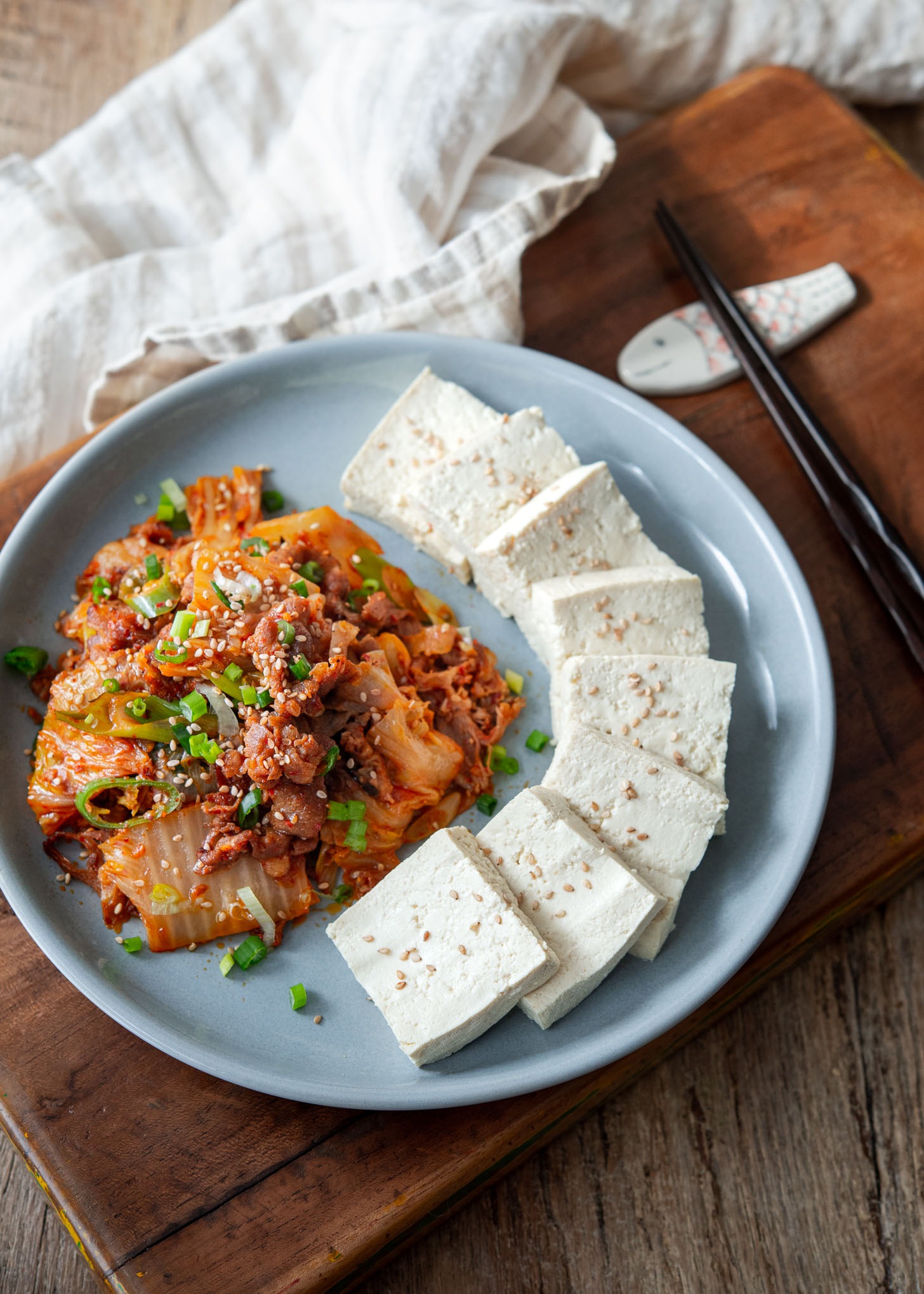 Korean tofu slices and stir fried kimchi are presented together on a plate.