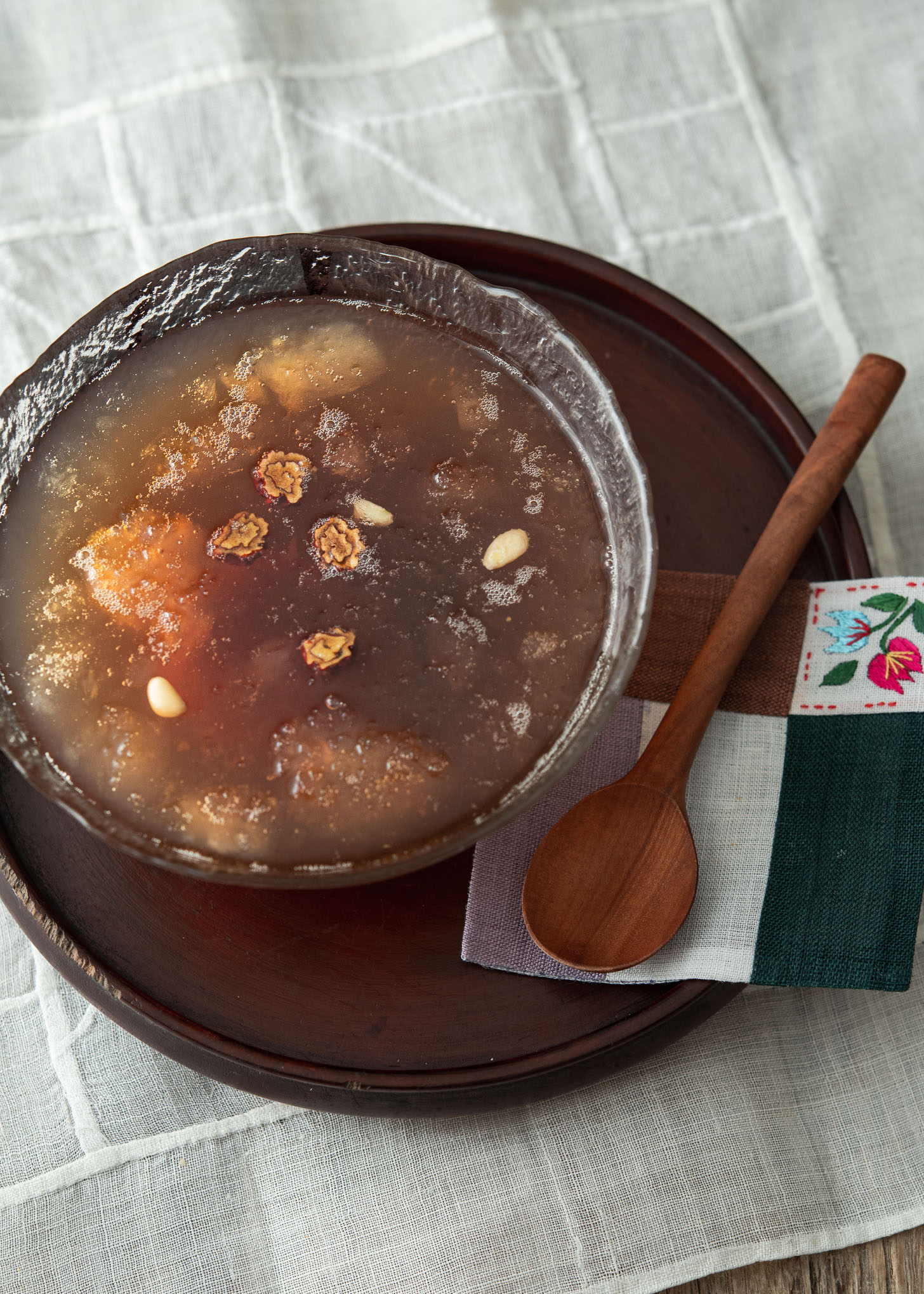 Cold Korean cinnamon punch (sujeonggwa) is served in a glass bowl with a spoon on the side.