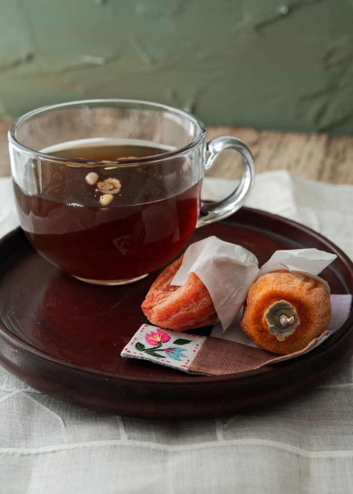 Hot Korean cinnamon ginger tea is served with dried persimmon on the side.