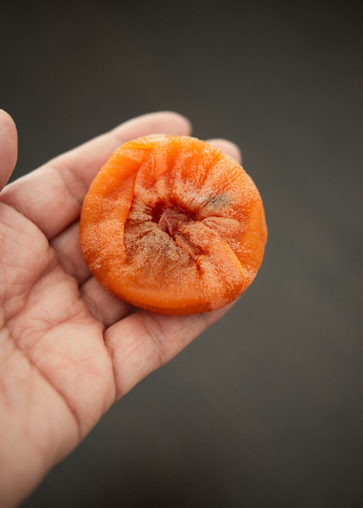 The sstem is removed from dried persimmon and flattened with a hand.