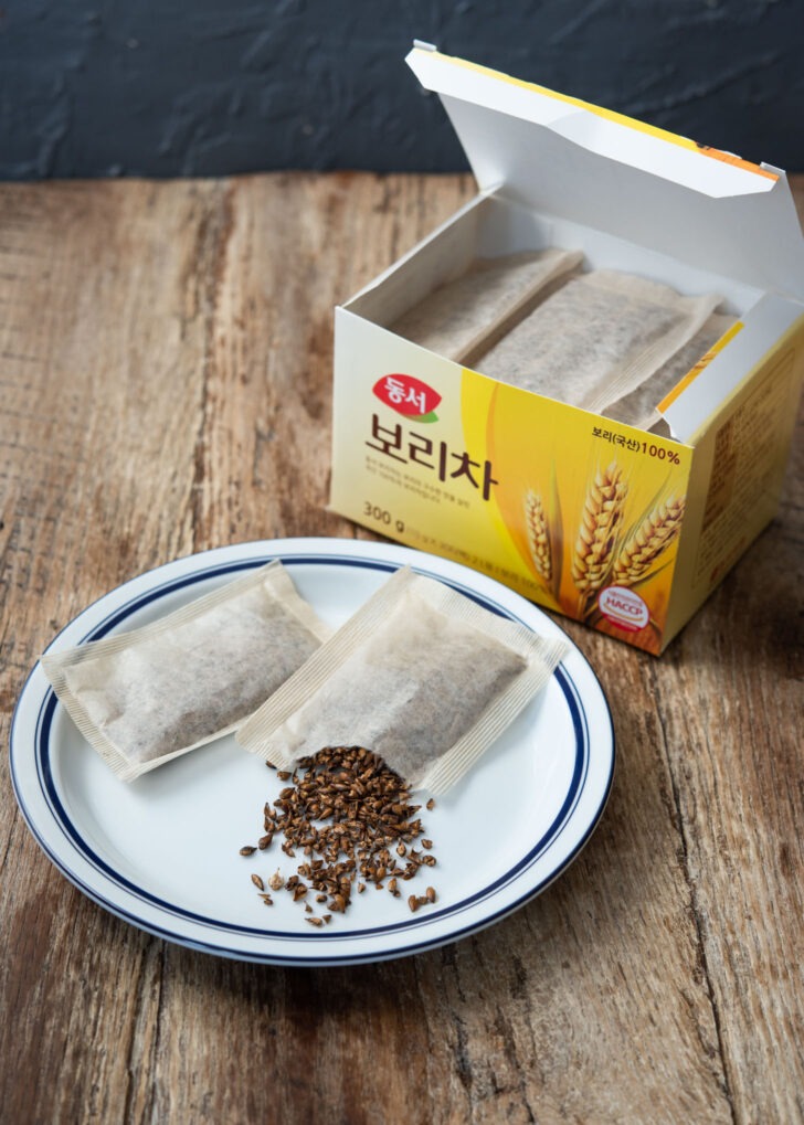 Barley tea bag is torn and exposing the crushed roasted barley inside.