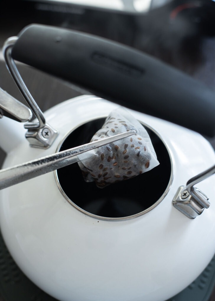 Barley tea bag being removed from a tea kettle.