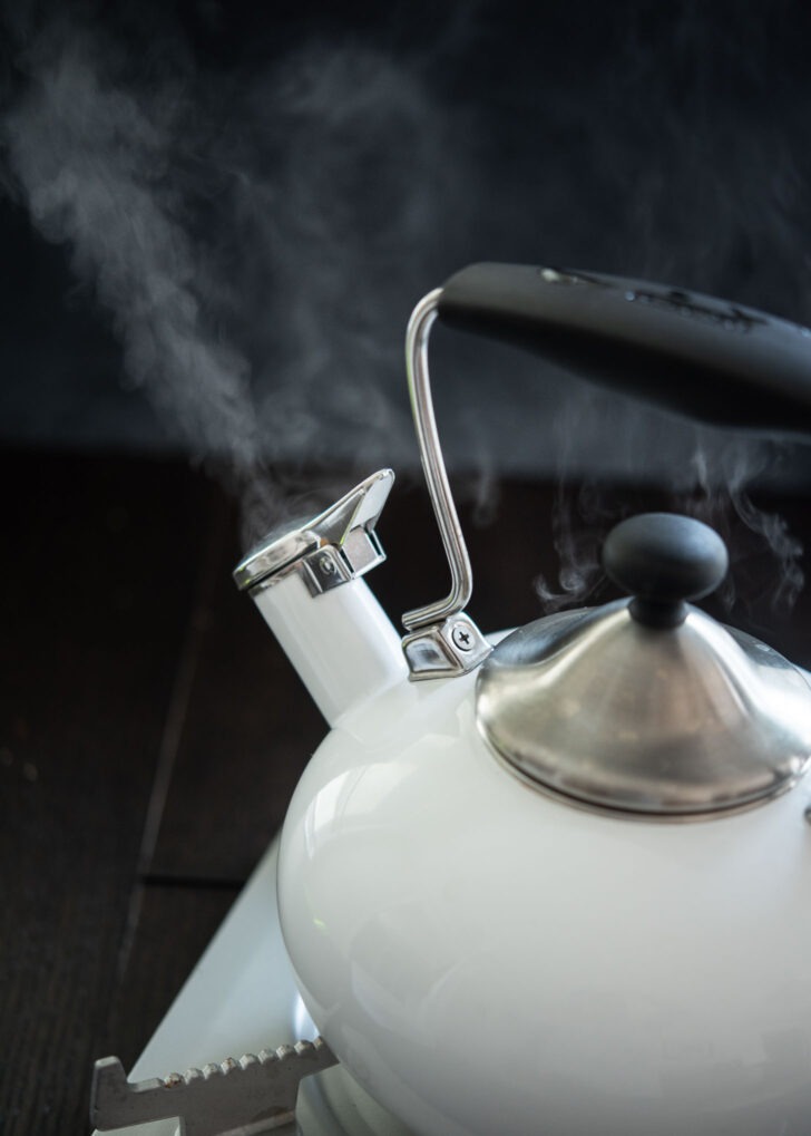 A tea kettle is boiling water and the steam is coming out of the spout.