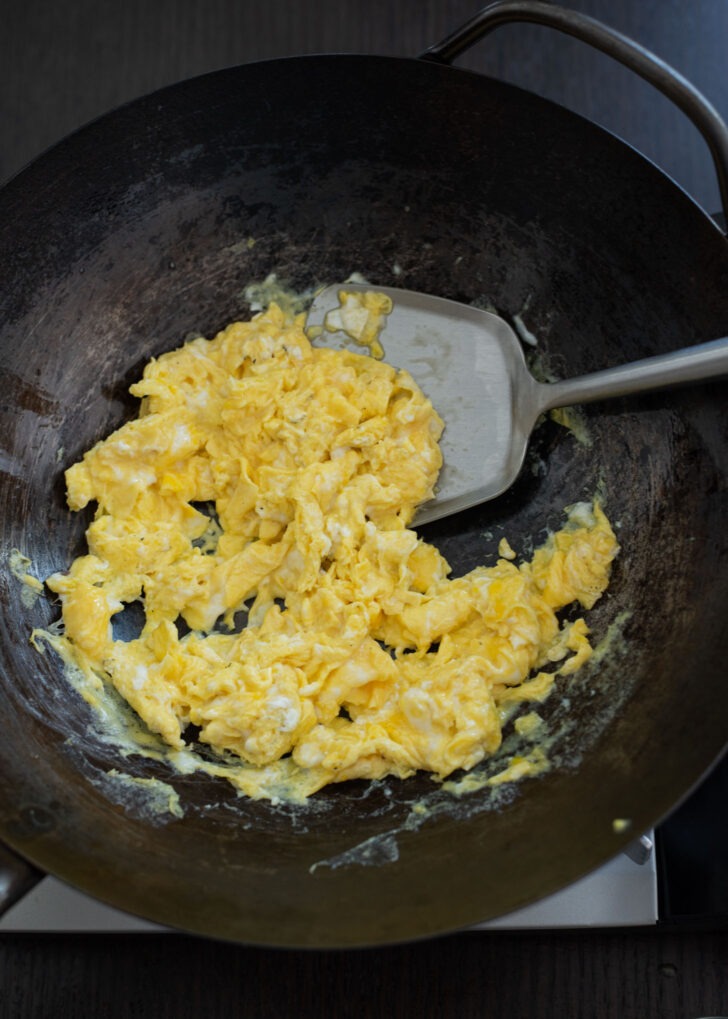 Egg is scrambled in a wok.