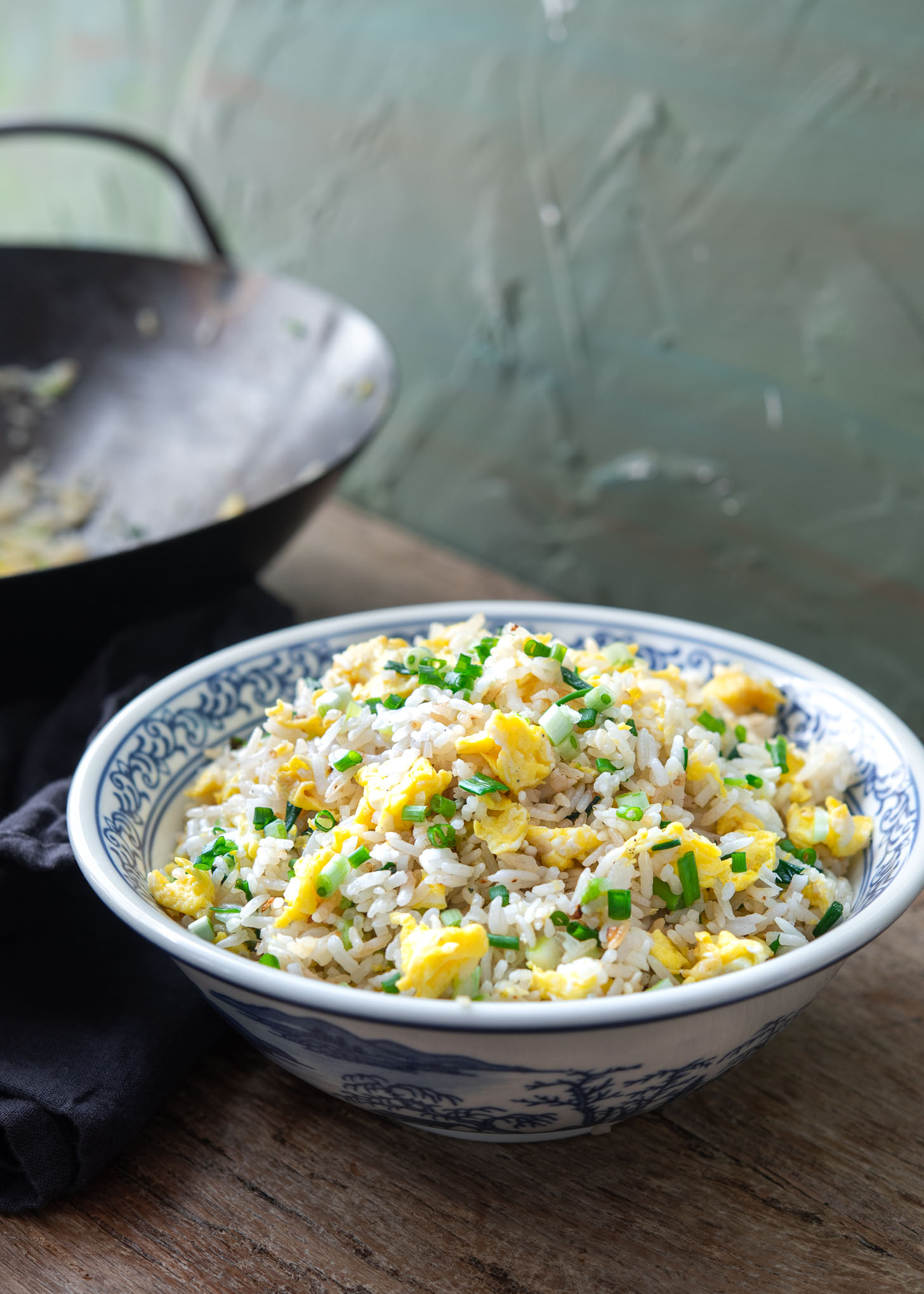 Egg fried rice is plated in a blue and white bowl.
