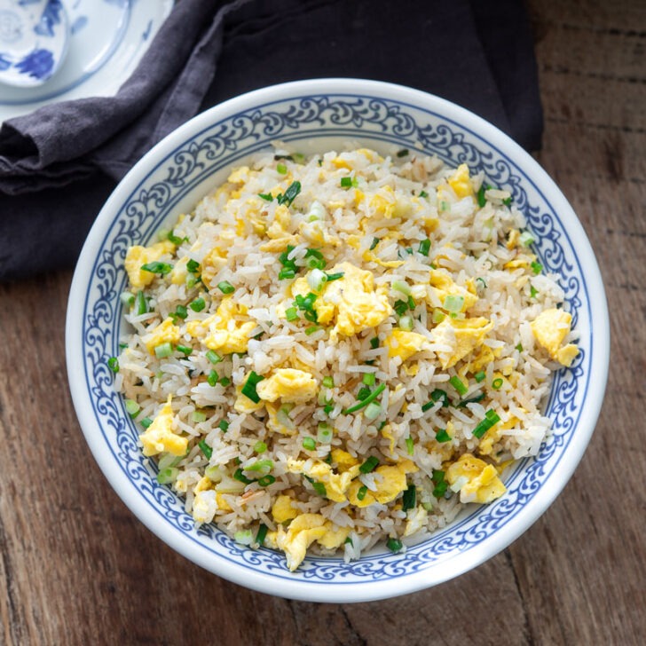 A bowl of egg fried rice is garnished with green onion.