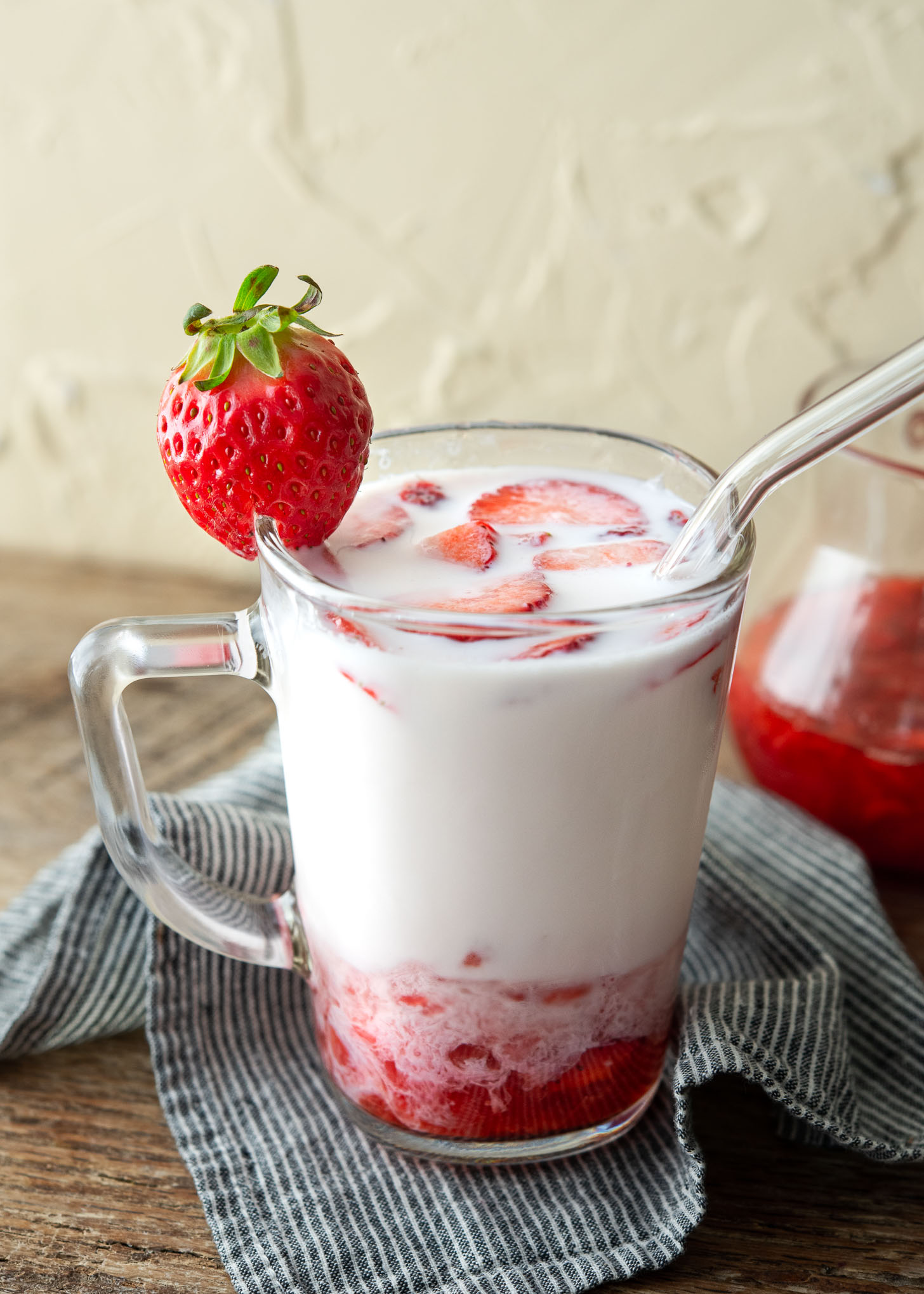 Milk and fresh strawberry syrup marbled together in a glass cup.