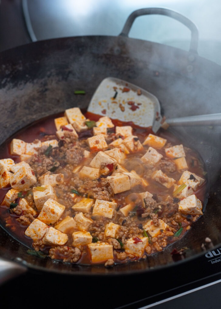 Mapo tofu being simmered in a wok.