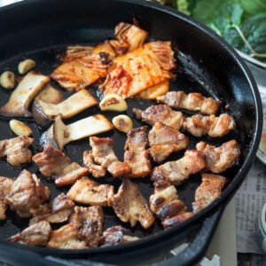 Korean samgyupsal with grilled pork belly and kimchi in a pan