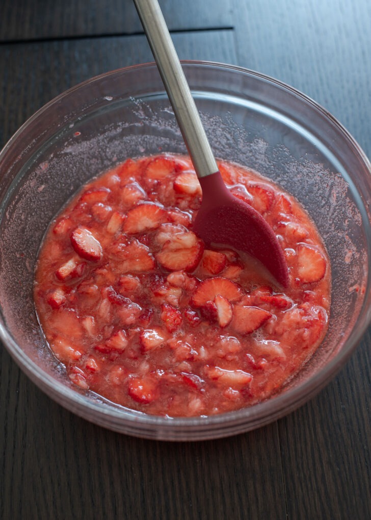 Fresh strawberry syrup mixed with a spoon in a mixing bowl.