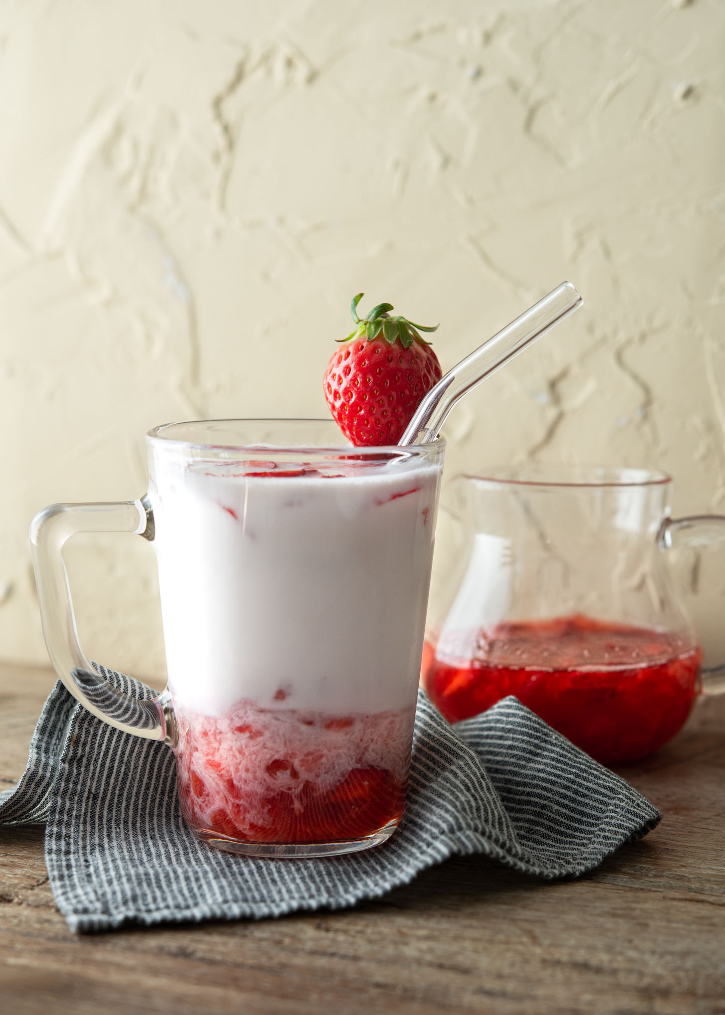 Korean strawberry milk in a glass cup garnished with a piece of strawberry.