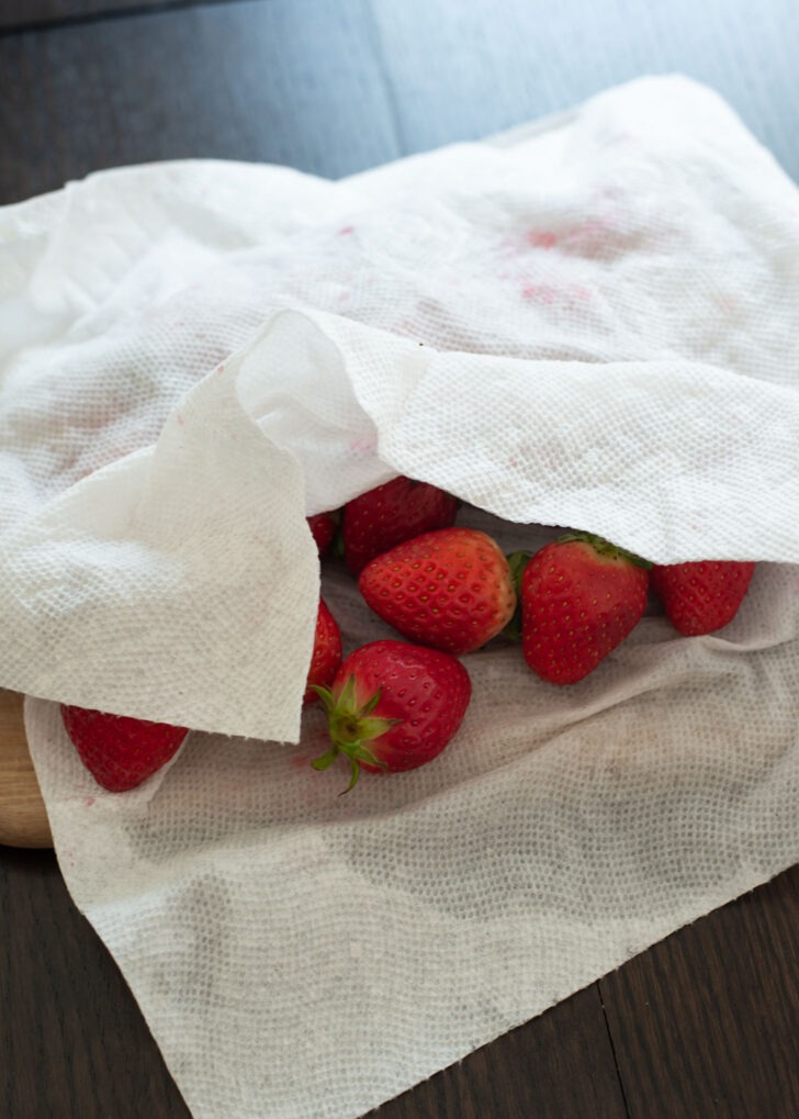 A paper towel is wiping off the extra moisture of fresh strawberries.