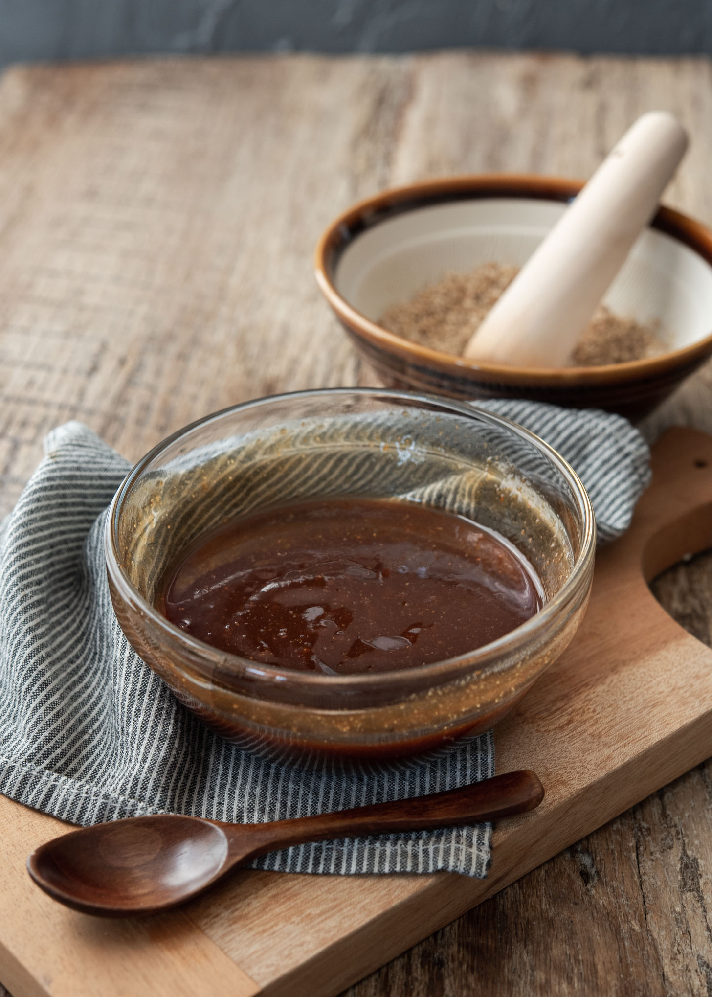 Homemade Tonkatsu sauce in a bowl is next to the crushed sesame seeds.