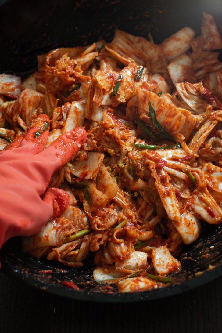 Cabbage coated with kimchi paste to make vegan kimchi.