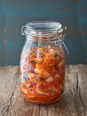 Vegan kimchi is stored and is fermenting in a glass jar.