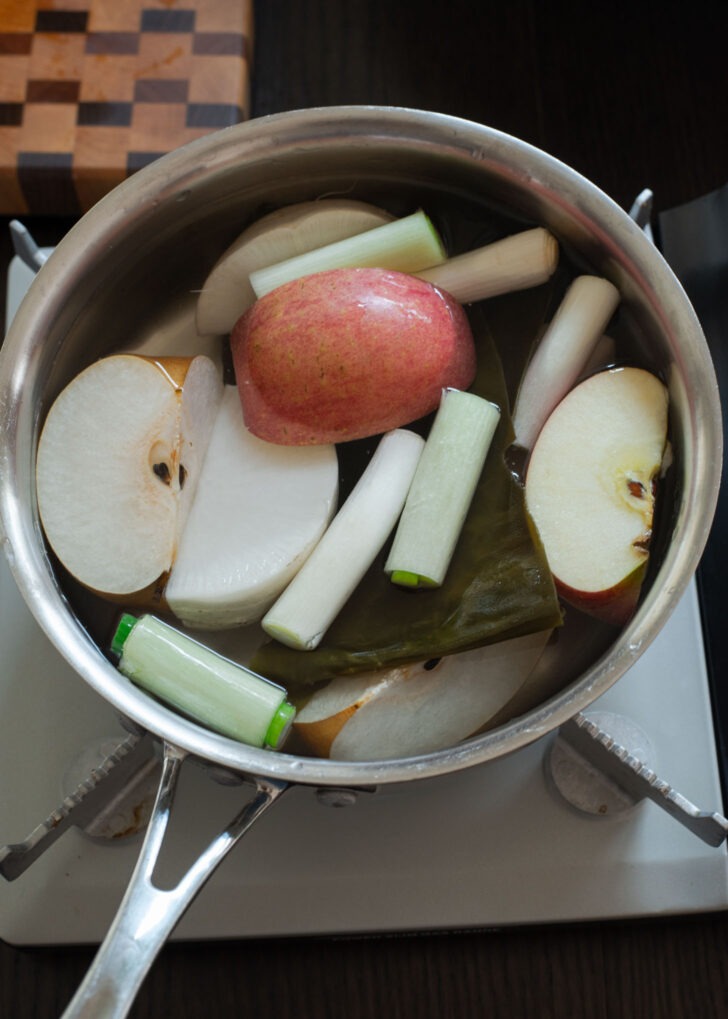 A variety of vegetables and fruits are added to a pot to make stock for kimchi.