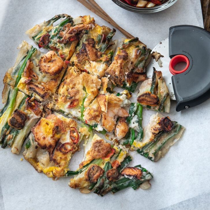 Pajeon with seafood is cut into slices and served with dipping sauce.
