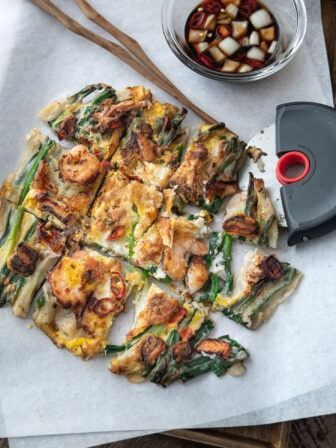 Pajeon with seafood is cut into slices and served with dipping sauce.