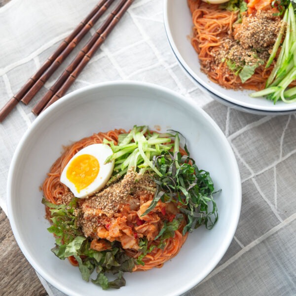 Bibim guksu (Korean cold noodles) garnished with salad vegetables and egg.