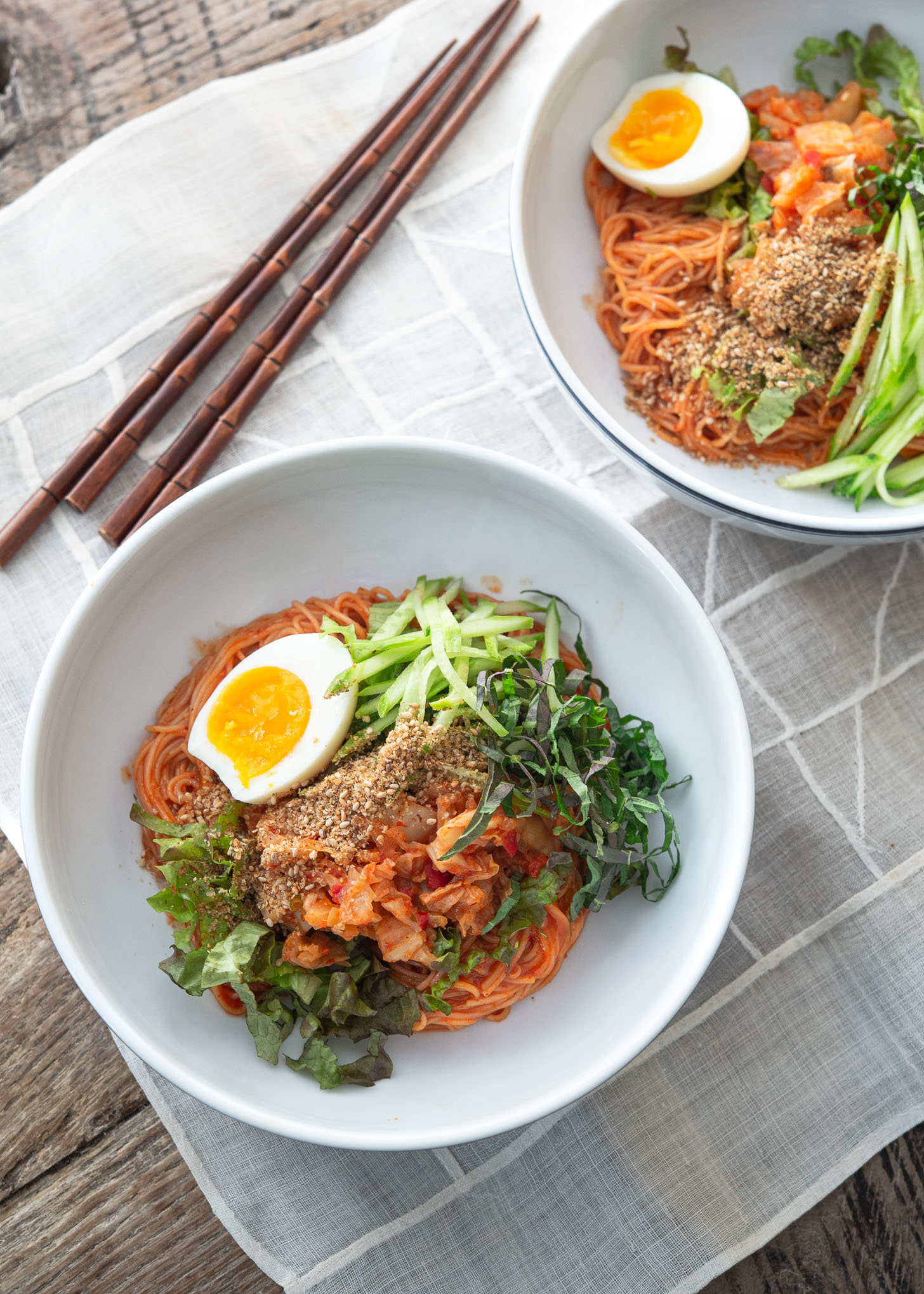 Bibim guksu (Korean cold noodles) garnished with salad vegetables and egg.