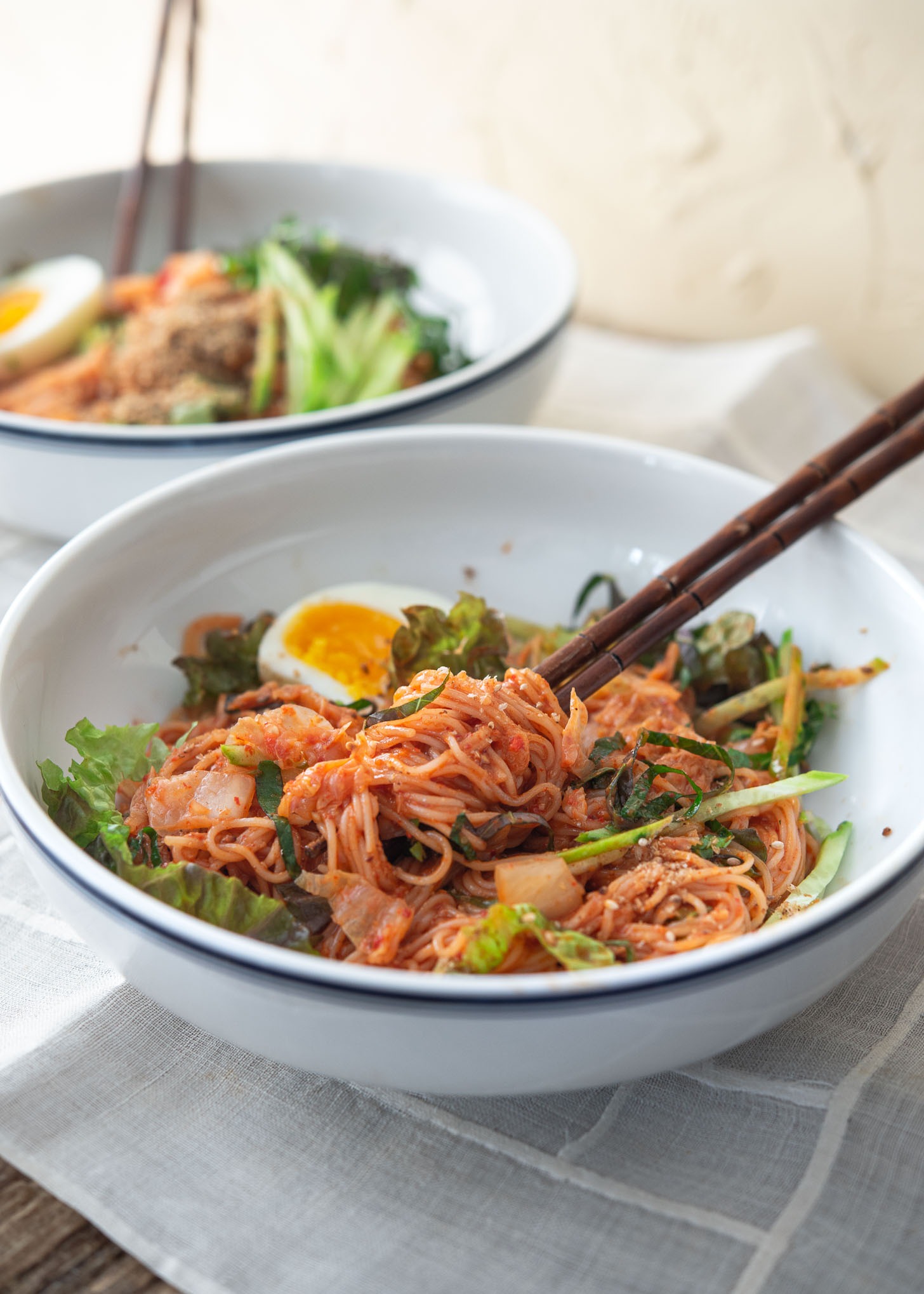A bowl of spicy Korean cold noodles with chopsticks.