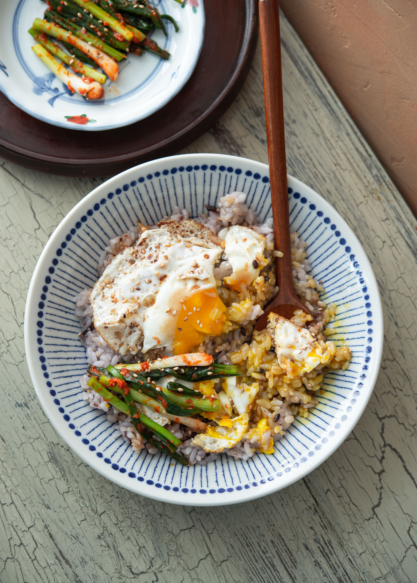 Gyeran bap topped with green onion kimchi as Korean eggs rice breakfast.