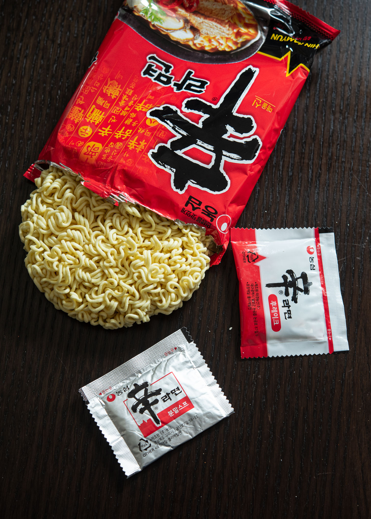 A packet of Korean instant ramen (ramyeon) opened and showing the noodles and seasoning packets.