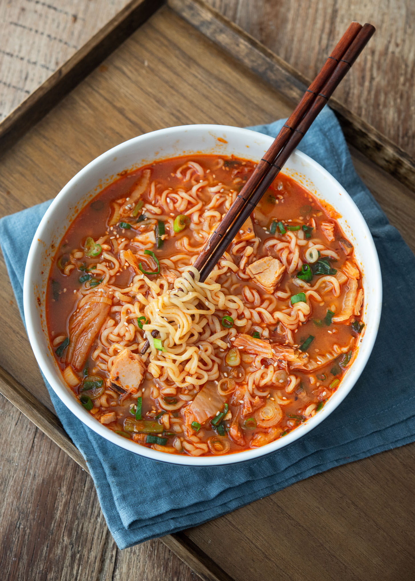 Chopsticks twirling kimchi ramen noodles.