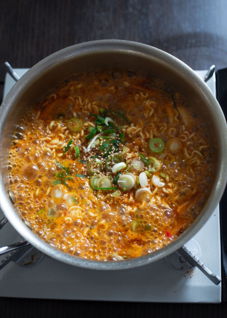 Chopped green onion, sesame oil, and sesame seeds are added to kimchi ramen.