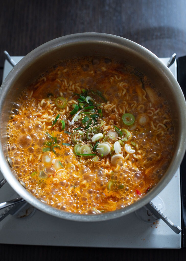 Chopped green onion, sesame oil, and sesame seeds are added to kimchi ramen.