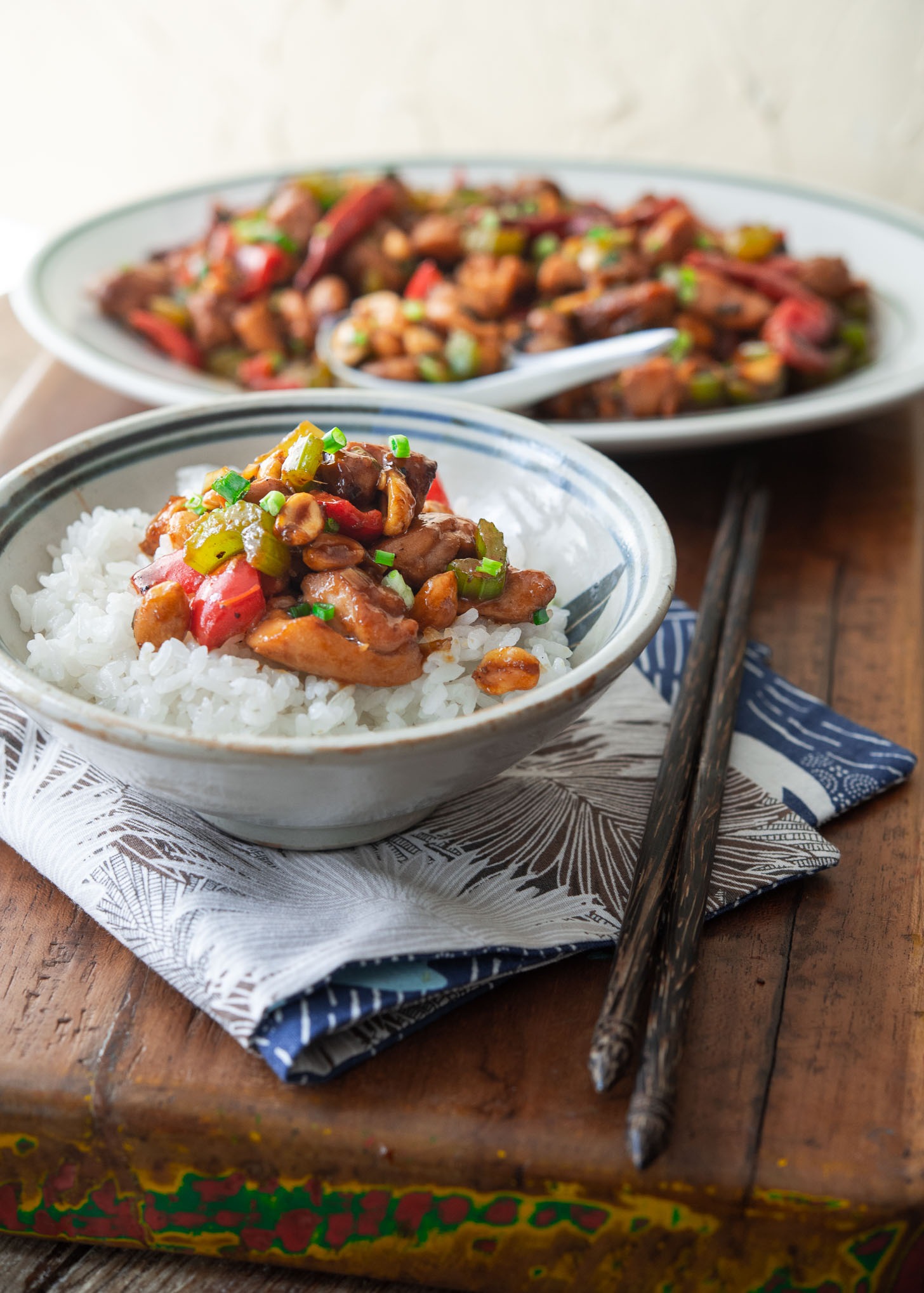 A bowl of white rice topped with kung pao chicken.