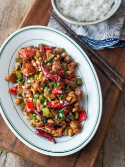 Kung pao chicken is served on a platter with a bowl of rice on the side.