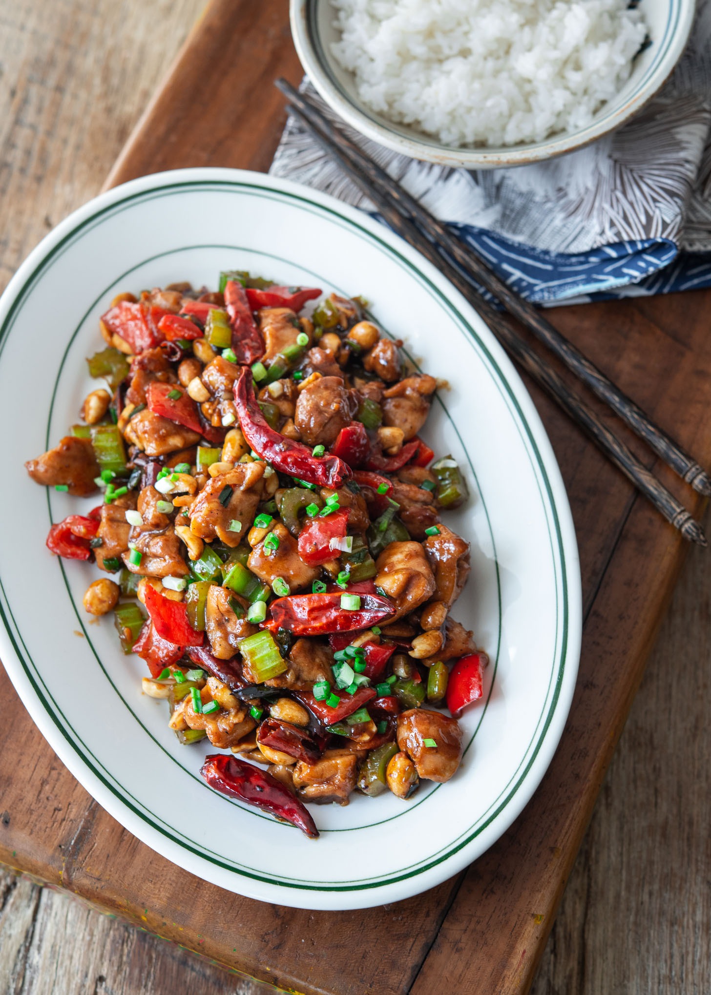 Kung pao chicken served in a white oval platter with chopsticks on the side.