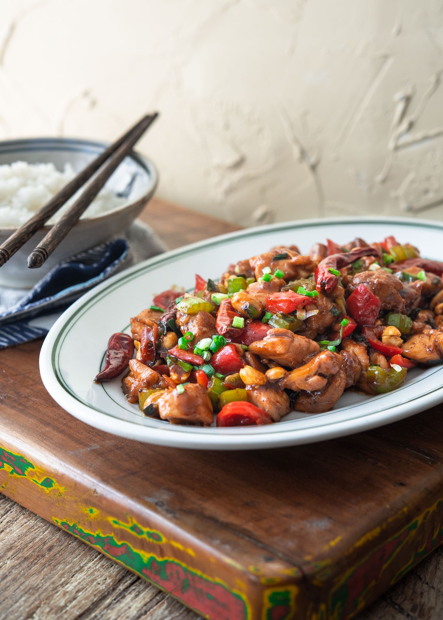 A plate of Kung Pao chicken presented with a bowl of rice.