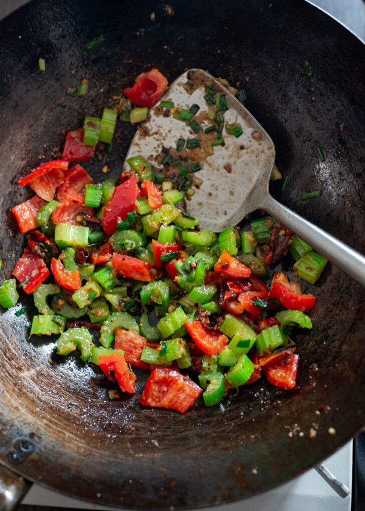 Celery and red pepper added to the aromatics in a wok.