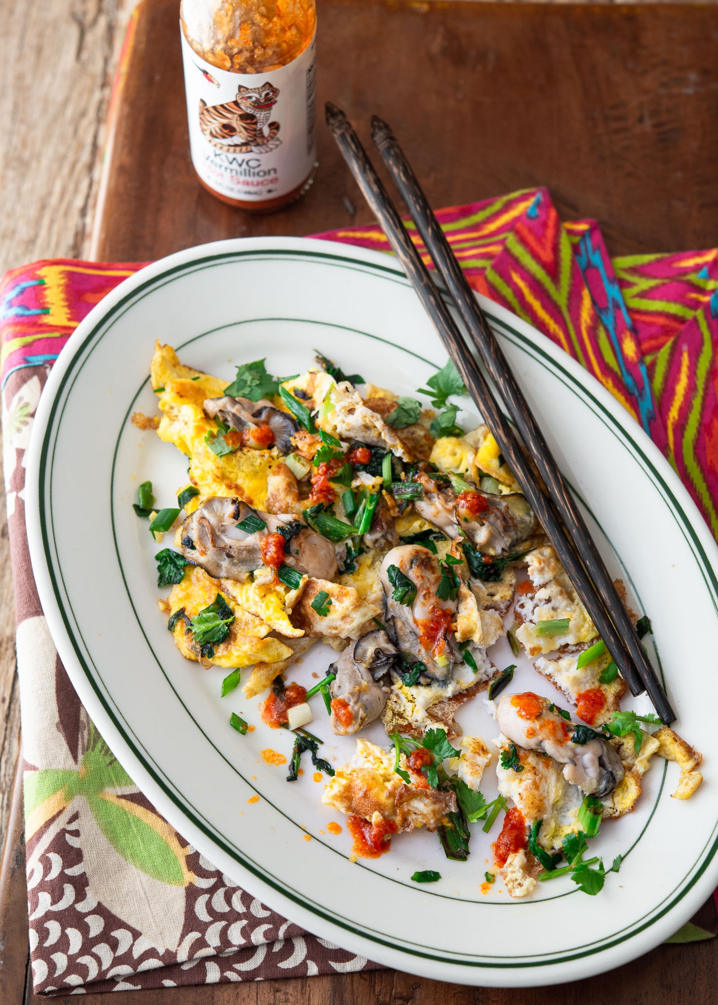 Hot sauce drizzled over oyster omelette in a serving dish.