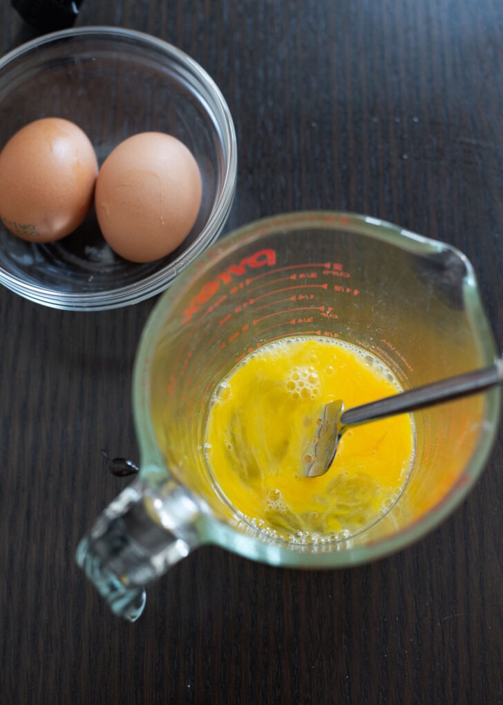 Eggs beaten with a fork in a mixing cup.