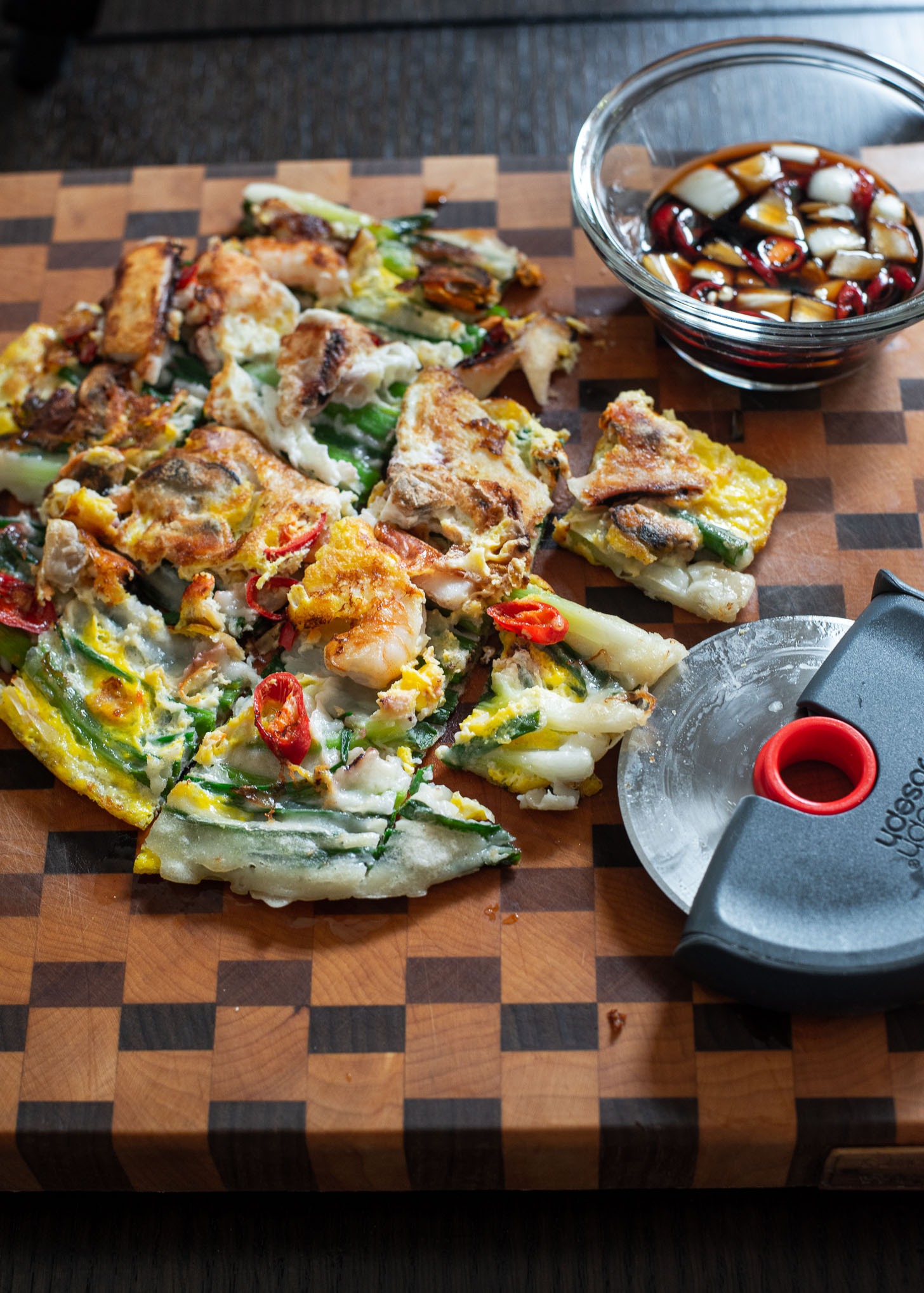 Seafood pajeon sliced into serving pieces using a pizza cutter.