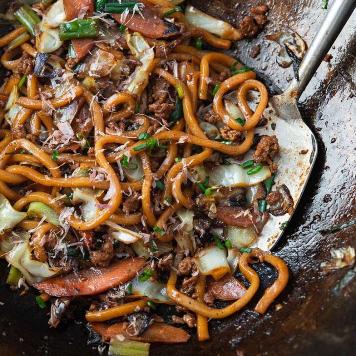 Stir-fried yaki udon noodles with pork and vegetables in a wok.